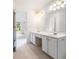 Bathroom featuring dual sinks, white cabinets and countertops, and an open doorway to a bedroom at 2910 Waverly Place Dr, Dacula, GA 30019