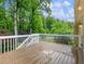 A spacious wooden deck with white railing offers a serene view of lush greenery and blue skies at 2910 Waverly Place Dr, Dacula, GA 30019