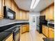 This kitchen features black appliances, wood cabinets, black countertops, and wood floors at 2910 Waverly Place Dr, Dacula, GA 30019