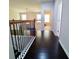 Upstairs hallway with dark wood floors, decorative railing, and a view into a living area at 3943 Ridge Grove Way, Suwanee, GA 30024