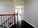 Hallway with dark wood floors, decorative railing, and a view into a bedroom at 3943 Ridge Grove Way, Suwanee, GA 30024