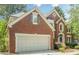 Charming brick two-story home featuring an attached garage and an arched entryway, complemented by mature landscaping at 425 Fieldstone Lndg, Alpharetta, GA 30005