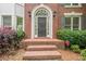 Close-up of a brick home's arched doorway, flanked by lush greenery and offering a welcoming entrance at 425 Fieldstone Lndg, Alpharetta, GA 30005