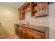Close-up of the wet bar featuring dark wooden cabinets, a granite countertop, and a mosaic backsplash at 425 Fieldstone Lndg, Alpharetta, GA 30005
