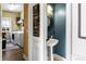A powder room with a pedestal sink, a round mirror, and a laundry room in the background at 5105 Riverthur Pl, Duluth, GA 30096