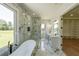 Stylish bathroom featuring marble walls, a soaking tub, glass shower, double vanity, and a separate closet for storage at 972 Auburn Rd, Dacula, GA 30019