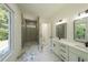 Modern bathroom featuring a glass-enclosed shower, dual sinks, and large windows at 972 Auburn Rd, Dacula, GA 30019