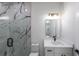Modern bathroom featuring a marble tiled shower with glass door and vanity with black hardware at 972 Auburn Rd, Dacula, GA 30019