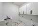 Clean laundry room featuring marble floors, sleek cabinetry, and modern fixtures at 972 Auburn Rd, Dacula, GA 30019