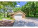 View of the home's brick garage and paved driveway surrounded by lush greenery at 1296 Carman Se Ct, Conyers, GA 30013