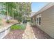 Landscaped backyard featuring a stone pathway, mature trees, a grill, and a view of the home's exterior at 1657 Williams Mill Way, Dacula, GA 30019