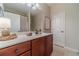 Well-lit bathroom with a cherry vanity, white countertop, modern fixtures, and a large mirror at 1657 Williams Mill Way, Dacula, GA 30019