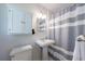 Well-lit bathroom with a pedestal sink, medicine cabinet, and shower-tub with gray and white striped curtain at 1890 Silvastone Dr, Decatur, GA 30033