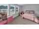 Bedroom with gray walls, carpet, and bed with a pink quilt near three sunny windows at 201 Kingfisher Walk, Covington, GA 30014