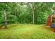 Large grassy backyard featuring mature trees and stairs leading to a deck at 2430 Harbin Springs Cv, Dacula, GA 30019