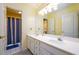 Bright bathroom featuring double sinks, white cabinets and a shower/tub combo with blue curtain at 2430 Harbin Springs Cv, Dacula, GA 30019