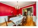 Formal dining room with red walls, hardwood floors, and chandelier lighting at 2430 Harbin Springs Cv, Dacula, GA 30019