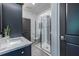 Modern bathroom featuring dark blue cabinets, a glass shower, and a stylish interior door, offering a sleek, updated space at 399 Pratt Se Dr # 910, Atlanta, GA 30315