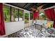 Relaxing sunroom with red curtains, ceiling fan, black and white floral patterned rug, and view to backyard at 104 River Creek Dr, Woodstock, GA 30188