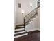 Elegant staircase featuring dark wood steps, white risers, and decorative black iron railing with wall sconces at 3280 Stillhouse Se Ln # 401, Atlanta, GA 30339