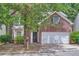 Two-story brick home featuring an attached two-car garage and a well-manicured lawn at 7078 Ravenwood Ln, Lithonia, GA 30038