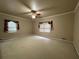 Large carpeted bedroom with a ceiling fan, neutral walls, and two windows at 1935 Lamp Post Ln, Lawrenceville, GA 30043