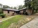 Charming brick ranch with a well-manicured lawn and mature trees, and a driveway to the right at 1935 Lamp Post Ln, Lawrenceville, GA 30043