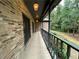 Exterior brick side porch with dark trim, painted railings, and views of the surrounding wooded lot at 1935 Lamp Post Ln, Lawrenceville, GA 30043