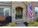 Covered front porch with brick detail and a decorative front door, trimmed with plants at 225 Sundance Dr, Woodstock, GA 30188