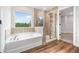 A modern bathroom features a soaking tub and glass-enclosed shower with tile surround at 2889 Windsor Knoll Dr, Dacula, GA 30019