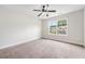 A bright and airy bedroom features neutral carpet, ceiling fan, and a window with a view of the neighborhood at 2889 Windsor Knoll Dr, Dacula, GA 30019