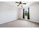 A bright bedroom features neutral carpet, a ceiling fan, and a window bringing in natural light at 2889 Windsor Knoll Dr, Dacula, GA 30019