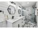 Modern bathroom with double sinks, white cabinets, hexagon mirrors and a marble shower at 1477 Spruce Se Dr, Smyrna, GA 30080