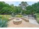 Beautiful backyard space with stone fire pit, seating, inground pool, lush landscaping, and mature trees at 4135 Creekwood Dr, Cumming, GA 30041