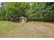Backyard with a storage shed among lush trees and a well-maintained lawn at 4135 Creekwood Dr, Cumming, GA 30041