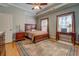 Cozy bedroom with wood furniture, ceiling fan, large area rug, and natural light from two windows at 15 Walnut Ridge Way, Covington, GA 30014