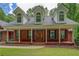Home showcasing welcoming front porch with columns, brick accents, and a decorative door at 15 Walnut Ridge Way, Covington, GA 30014