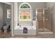 A bright bathroom with a soaking tub, a separate shower stall, and a large window with a view at 214 Crestmont Way, Canton, GA 30114