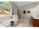 Bright bathroom with a soaking tub and a separate glass shower, and a scenic view from the arched window at 214 Crestmont Way, Canton, GA 30114