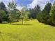 A large, well-maintained front yard features vibrant green grass and mature trees, offering a serene, park-like setting at 4380 Highway 138, Oxford, GA 30054