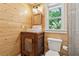 Rustic bathroom with wood-paneled walls, a unique vanity, and a toilet under a window at 1016 Green Dr, Canton, GA 30114