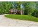 House with large deck set amongst the trees with green lawn and gravel driveway at 1016 Green Dr, Canton, GA 30114