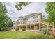 Back of house features a large deck with stairs to the backyard, surrounded by lush landscaping and mature trees at 2555 Chattahoochee Ln, Cumming, GA 30041