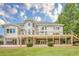 Back of house features a large deck with stairs to the backyard, surrounded by lush landscaping and mature trees at 2555 Chattahoochee Ln, Cumming, GA 30041
