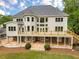 Back of house features a large deck with stairs to the backyard, surrounded by lush landscaping and mature trees at 2555 Chattahoochee Ln, Cumming, GA 30041
