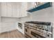 Close up of professional grade stainless steel stove and cooktop against white subway tile backsplash at 2555 Chattahoochee Ln, Cumming, GA 30041