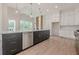 Spacious kitchen with black island, stainless appliances, white cabinetry, and light hardwood floors at 2555 Chattahoochee Ln, Cumming, GA 30041