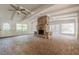 Open living room features a brick fireplace, exposed beams, hardwood floors, and ample natural light from surrounding windows at 2555 Chattahoochee Ln, Cumming, GA 30041