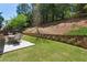 Well-maintained backyard showcasing a stone retaining wall, lush greenery, and a charming outdoor dining area at 1749 Grand Oaks Dr, Woodstock, GA 30188
