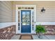 Close-up of a stylish front door with glass panels, brick accents and a potted plant at 1749 Grand Oaks Dr, Woodstock, GA 30188
